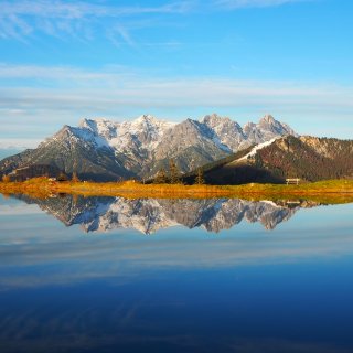 Verschneites Bergmassiv spiegelt sich im ruhigen Astbergsee.
