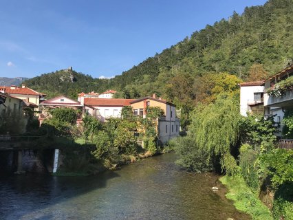 Das Bild zeigt
                           die Quellen des Flusses Vipava in der slowenischen Kleinstadt Vipava. Man sieht den Fluss und am Flussrand jeweils Bäume sowie
                           kleine Häuser.