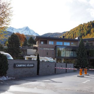 Einfahrt vom Camping Sölden mit Schranken, Rezeption sowie Bergpanorama im Hintergrund.
