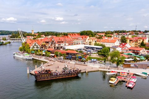 Luftbild auf die Stadt
                           Mikołajki im Nordosten Polens in Masuren. In dieser Stadt starten viele Ausflugsboote in die Masuren, im Vordergrund ein piratenähnliches
                           Ausflugsboot.