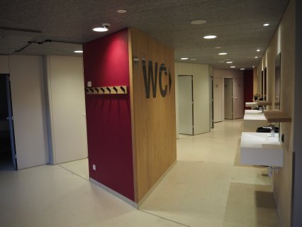 Sanitäranlagen des Tirol Camp Fieberbrunn. Man sieht Waschbecken, sowie das WC Zeichen/Hinweis