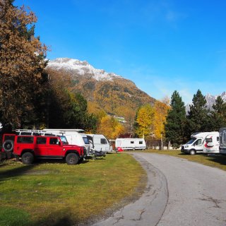Mit Fahrzeugen, Wohnwagen, Reisemobile Belegte Parzellen des Camping Sölden im Herbst sowie Berge im Hintergrund.
                           