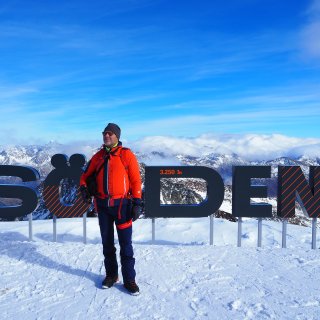 Person in Wanderkleidung steht im Schnee vor dem Schriftzug „Sölden
                           3.250 m“ und einem hochalpinen Bergpanorama.