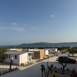 Mehrere Mobile Homes auf
                           dem Camping Resort Sibenik mit Blick auf das Meer. Die Unterkünfte sind zwischen Olivenbäumen und begrünten Wegen angeordnet,
                           im Hintergrund sind Wasser und eine vorgelagerte Insel zu sehen.