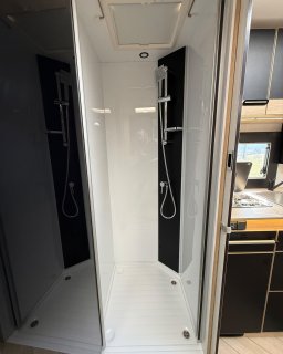 Separate Duschkabine im Chausson Titanium 640 mit
                           zwei Brauseeinheiten, dunklen Wandpaneelen und Dachfenster.