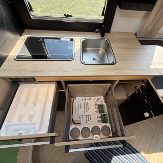 Geöffnete Küchenzeile des Chausson Titanium
                           640 mit Schubladen, Besteckeinsatz, Staufächern, Spüle und abgedecktem Kochfeld.