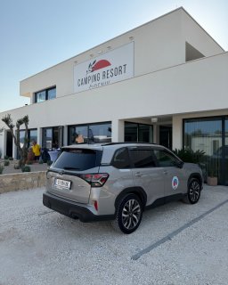 Modernes
                           Gebäude des Camping Resort Šibenik mit großem Resort-Schild an der Fassade. Vor dem Eingangsbereich steht ein grauer SUV mit
                           ÖCC-Logo auf der Fahrzeugtür, im Hintergrund sind mehrere Personen zu sehen.