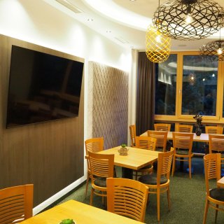 Speiseraum auf dem Campingplatz Camping Sölden: Raum mit Tischen und Stühlen, Lampen an der Decke sowie
                           Fernseher an der Wand.