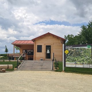 Holzgebäude mit überdachtem
                           Eingangsbereich, Sitzbank und Informationstafeln sowie einer großen Karte der Wexl Trails daneben.
