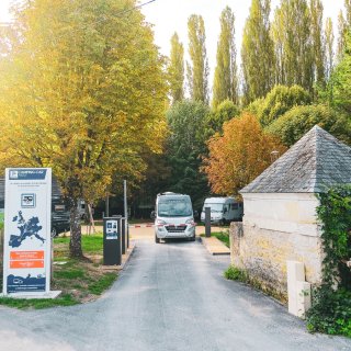 Einfahrt zu einem CAMPING-CAR PARK Wohnmobilstellplatz mit Schrankensystem. Zudem ist rechts von der Einfahrt
                           ein kleine Haus, links ein Baum und hinter den Schranken steht ein Wohnmobil. Einige Parzellen auf dem Stellplatz sind zudem
                           mit Wohnmobilen besetzt.
