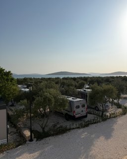 Stellplätze
                           für Reisemobile und Camper liegen zwischen Olivenbäumen direkt am Meer. Im Hintergrund sind die Küstenlandschaft und mehrere
                           vorgelagerte Inseln zu sehen.