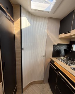Geschlossene, geriffelte Schiebetür
                           zwischen Küchenzeile und Heckbereich des Chausson Titanium 640, darüber ein Dachfenster.