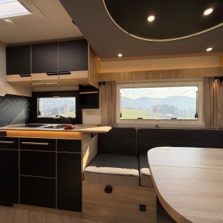 Küche und Sitzgruppe des Chausson Titanium
                           640 mit Oberschränken, Tisch und großen Fenstern.
