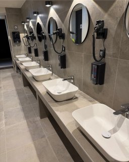 Waschbereich
                           der Sanitäranlagen im Camping Resort Šibenik mit mehreren Waschbecken, runden Spiegeln und fest installierten Haartrocknern.
                           Die Einrichtung ist modern gestaltet.