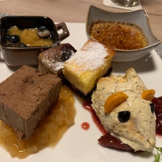 Dessertvariation mit Kuchen, Mousse, Crème
                           brûlée, Fruchtkompott und Beeren auf einem weißen Teller.