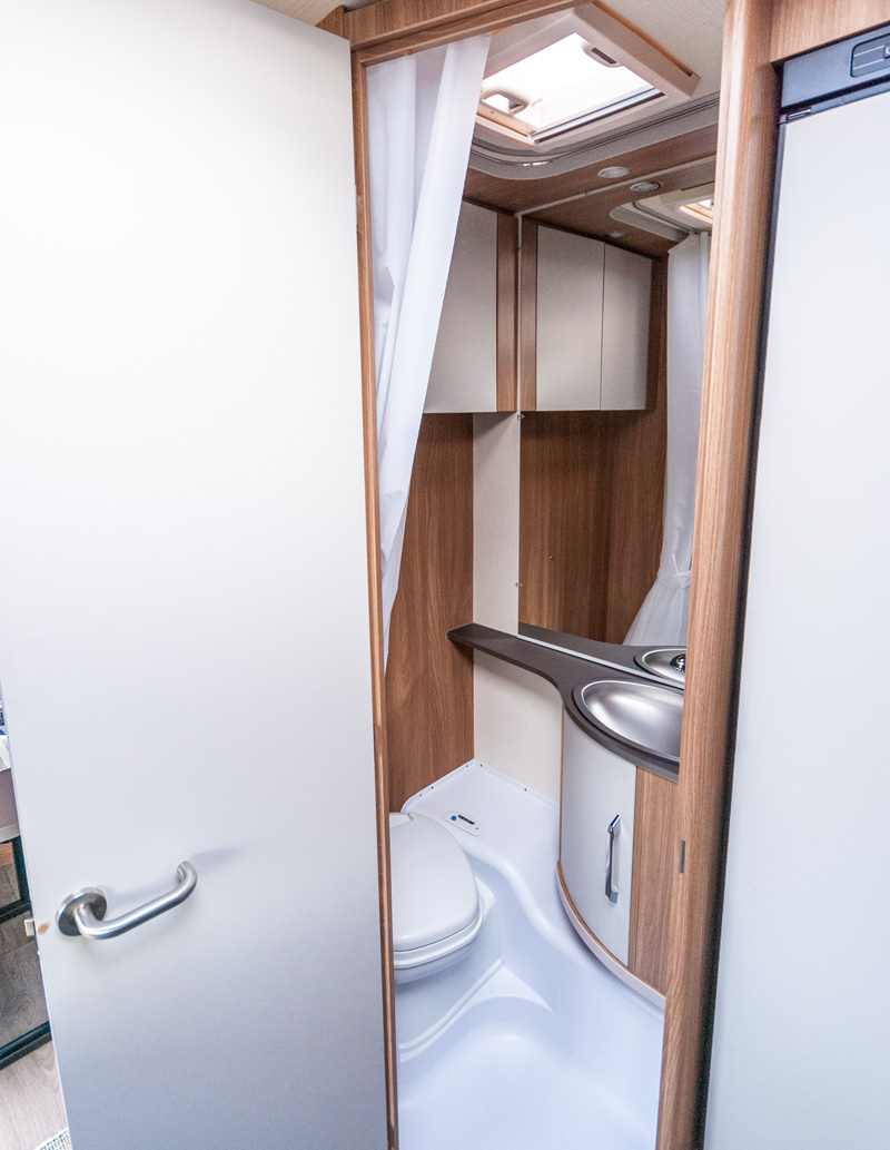 Eine aufgeräumte Nasszelle mit WC, Waschtisch und Dusche.