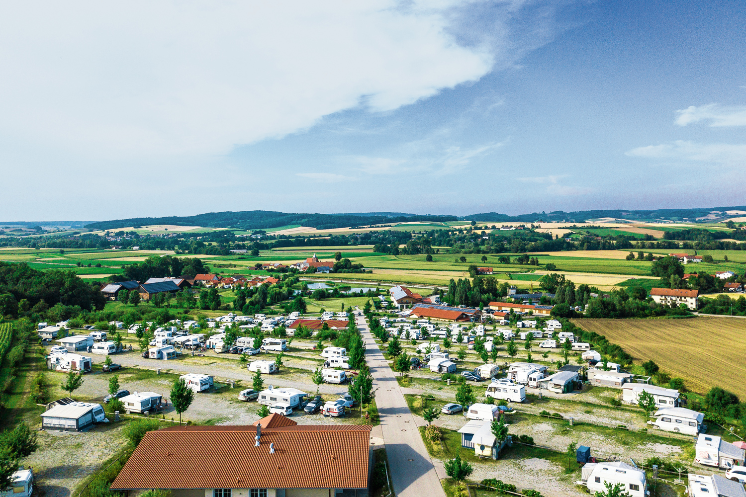 Stellplatzübersicht des Vital Camp Bayerbach mit vielen Wohnmobilen und Rezeptionsgebäude