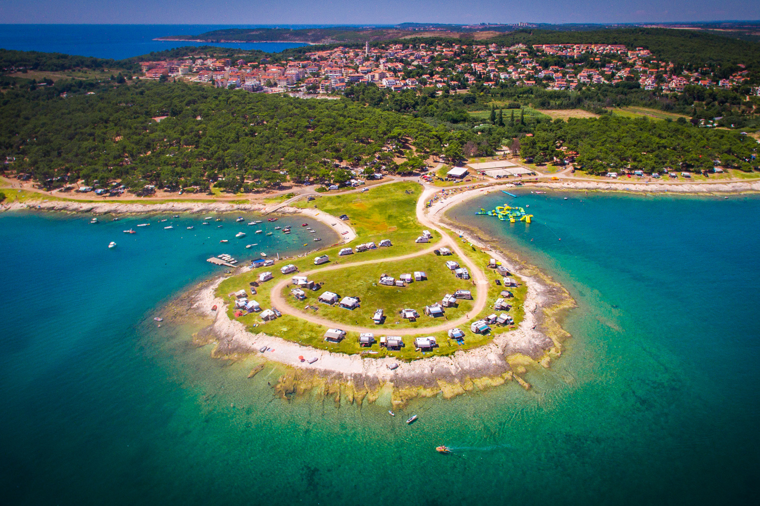 Luftbildaufnahme des Arena Stupice Campsite. Der Campingplatz liegt direkt am Meer mit Plätzen auf Wiese
                                 direkt am Wasser. Der REst vom Platz ist sehr stark mit Bäumen bewachsen.
