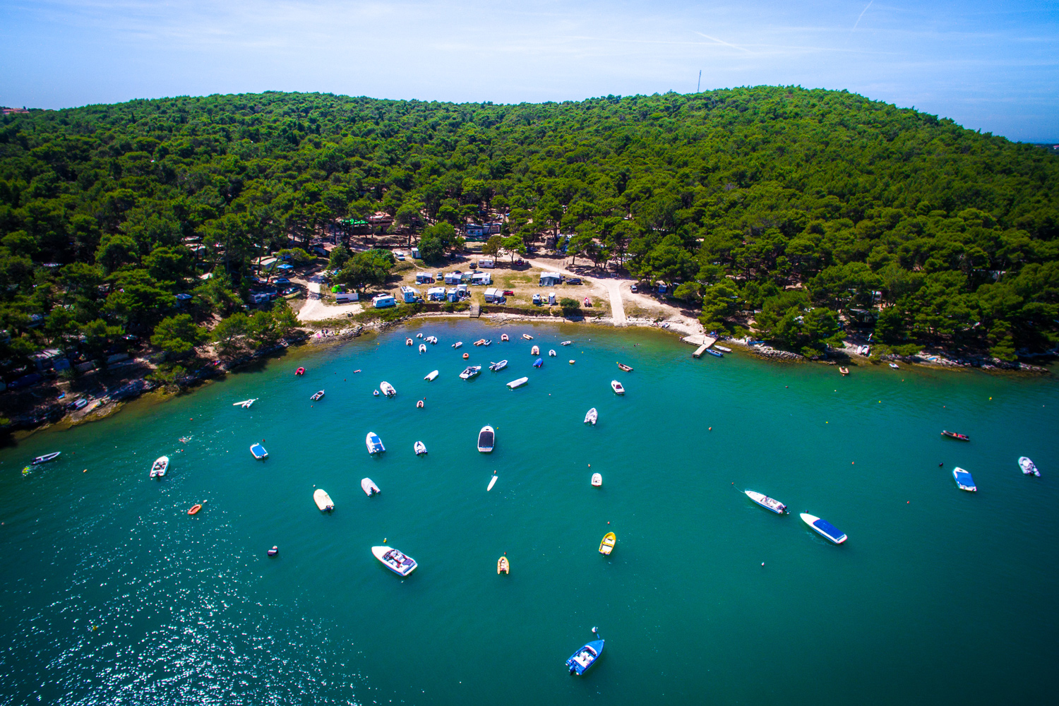 Luftbildaufnahme des Arena
                                 Tasalera Campsite. Der Campingplatz liegt an einer kleinen Bucht und ist stark bewaldet. In der Bucht stehen viele kleine
                                 Motorboote.