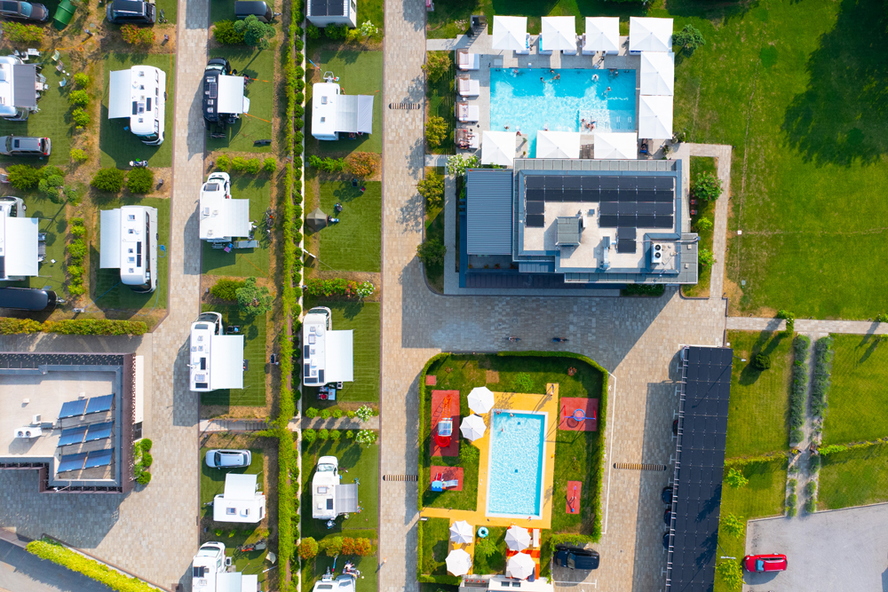 Luftbildaufnahme
des Campingresorts San Servolo in Kroatien. Auf der linken Seite des Bildes sind mit Wohnwägen und Wohnmobilen belegte Plätze
zu sehen, während auf der rechten Seite zwei Pools des Resorts abfotografiert sind.