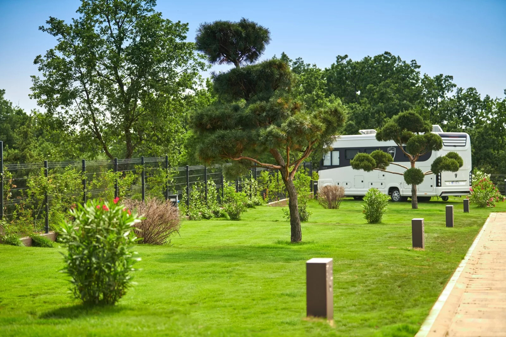 Mit Kunstrasen belegte und mit einzelnen Bäumen umgebene Stellplätze des Camping Resort San Servolo in Kroatien.
Auf einem der Stellplätze steht ein Wohnmobil.