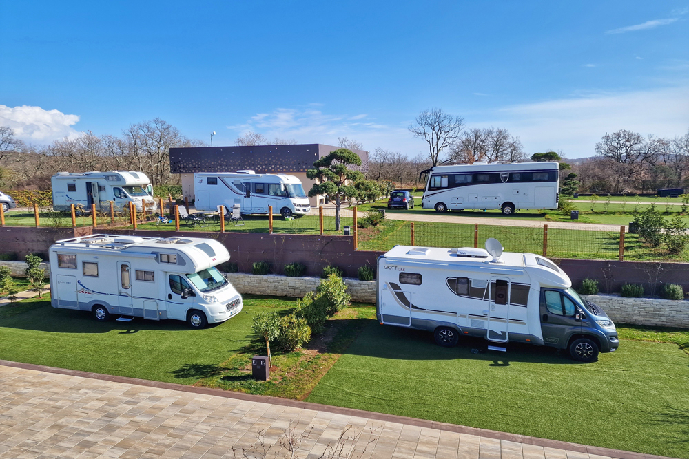 Wohnmobile, welche auf
mit Kunstrasen belegten Stellplätzen auf dem Resort San Servolo in Kroatien stehen. Zu sehen sind 6 Wohnmobile sowie ein kleiner
PKW.