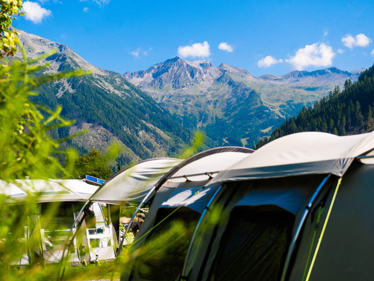 Zwei Zelte im Vordergrund und im Hintergrund die Bergkulisse in Mallnitz,
                           Steiermark vom Camping HOCHoben aus abfotografiert.